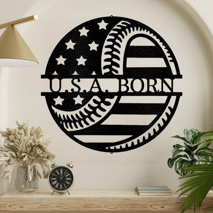 Black metal "U.S.A. BORN" sign with American flag and baseball stitching design.
