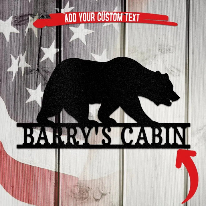 Black metal bear silhouette wall art with "Barry's Cabin" text, on a rustic American flag background.