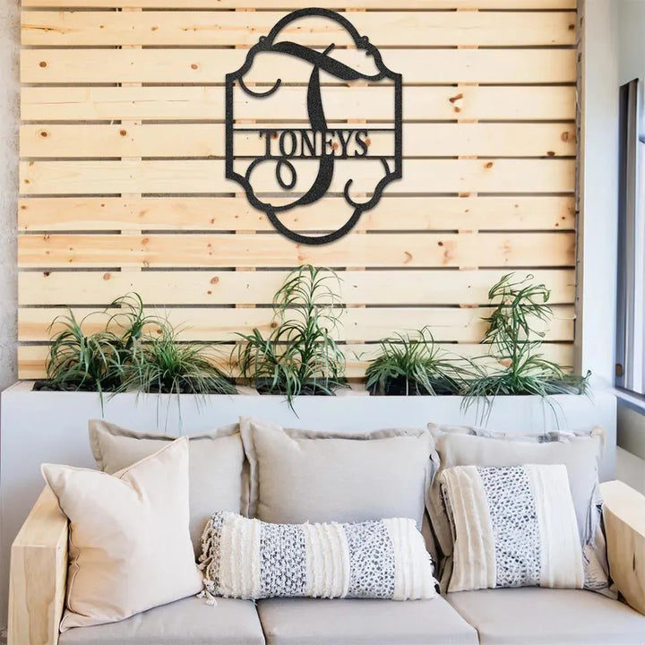 Black metal "TONEYS" family name plaque with a decorative "T" initial, mounted on a wooden slat wall.