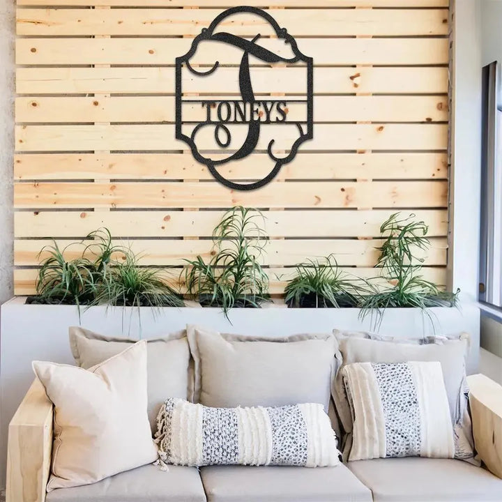 Black metal "TONEYS" family name plaque with a decorative "T" initial, mounted on a wooden slat wall.
