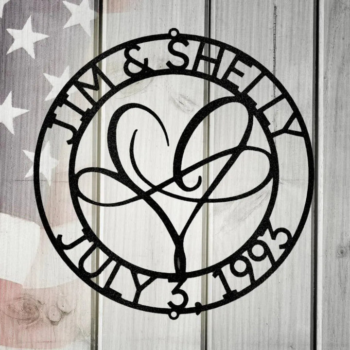 Black metal "Infinite Love Monogram" with names "Jim & Shelly" and date "July 3, 1993" encircling a heart design.
