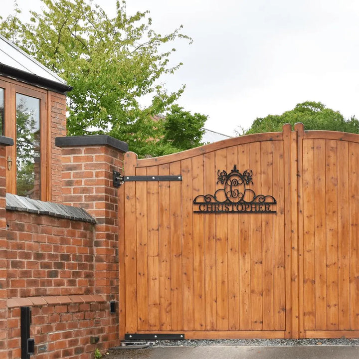 Black metal initial "C" and "CHRISTOPHER" name monogram wall art on a wooden gate.