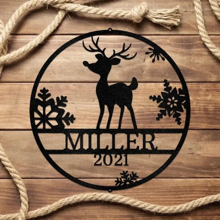 Black metal Rudolph reindeer monogram wall art with "MILLER 2021" text, snowflakes, on wood with rope.