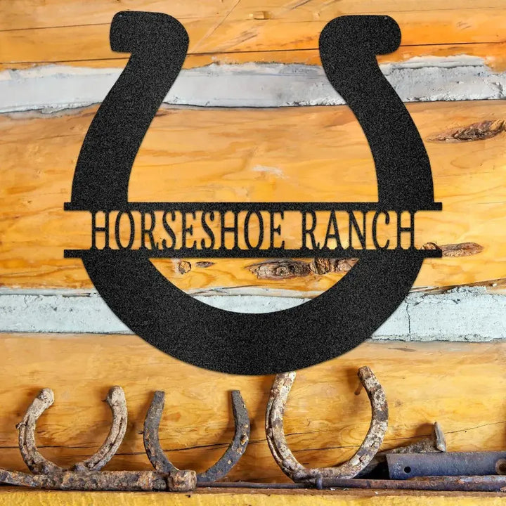 Black metal horseshoe monogram "HORSESHOE RANCH" sign on a rustic log wall.