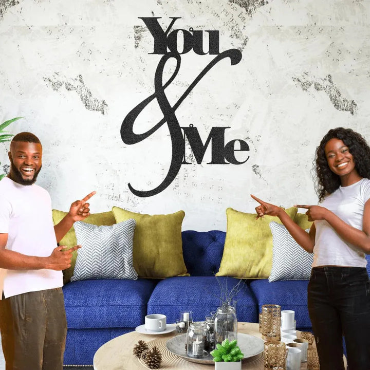 Black "You & Me" metal wall art with elegant script, displayed above a blue sofa.