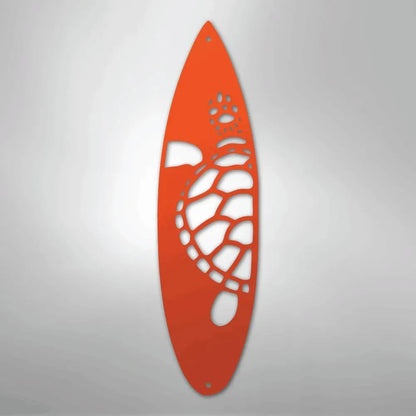 Orange metal wall art shaped like a surfboard with a cutout turtle design.