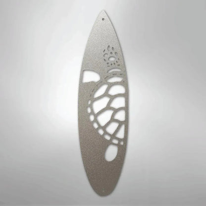 Silver metal surfboard wall art with a cutout turtle design.