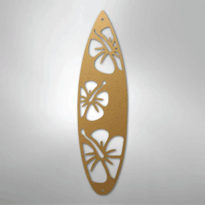 Gold metal surfboard wall art with three hibiscus flower cutouts.