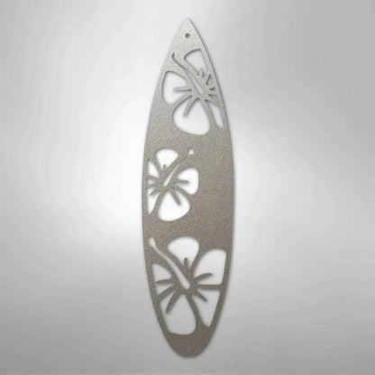Silver metal surfboard wall art with three cutout hibiscus flowers.