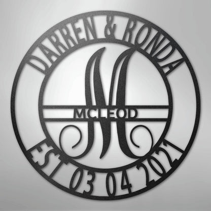 Black metal family name wall art with "Darren & Ronda," a large "M," "McLeod," and "Est. 03 04 2021" in a circular design.