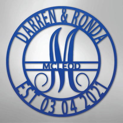 Blue metal family name wall art with "Darren & Ronda," a large "M," "McLeod," and "Est 03 04 2021" in a circular design.