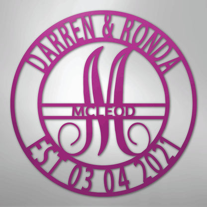 Pink metal family name wall art with "Darren & Ronda," a large "M," "McLeod," and "Est. 03 04 2021" in a circular design.