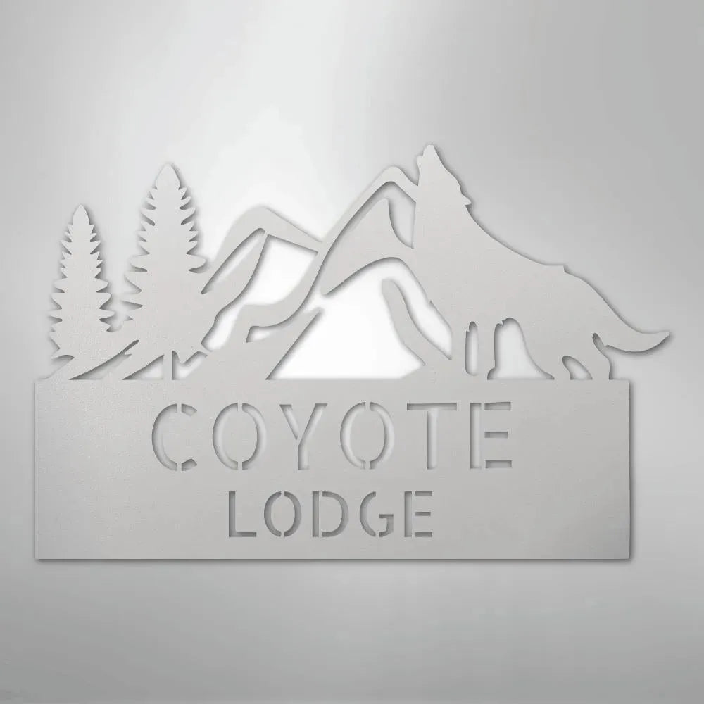 Gray metal wall art featuring a howling wolf, pine trees, mountains, and "COYOTE LODGE" text.