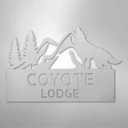 Gray metal wall art featuring a howling wolf, pine trees, mountains, and "COYOTE LODGE" text.