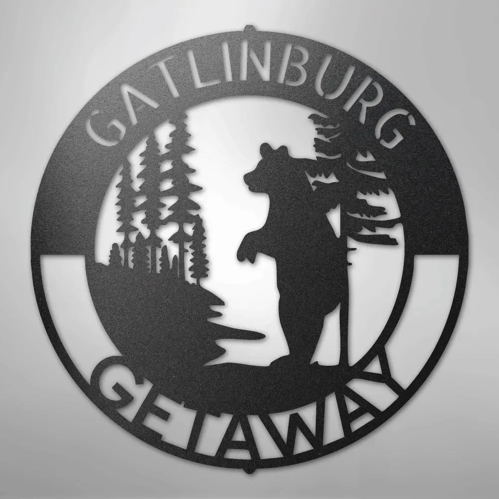 Black metal wall art: round "Gatlinburg Getaway" sign with a bear and pine trees.