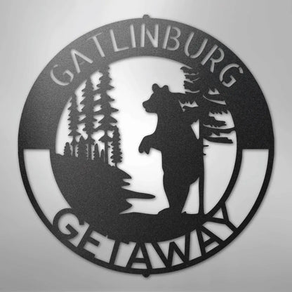 Black metal wall art: round "Gatlinburg Getaway" sign with a bear and pine trees.