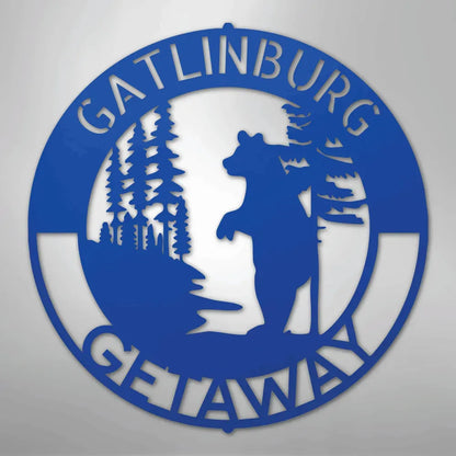 Blue metal wall art with "Gatlinburg Getaway" text, a bear, and pine trees.