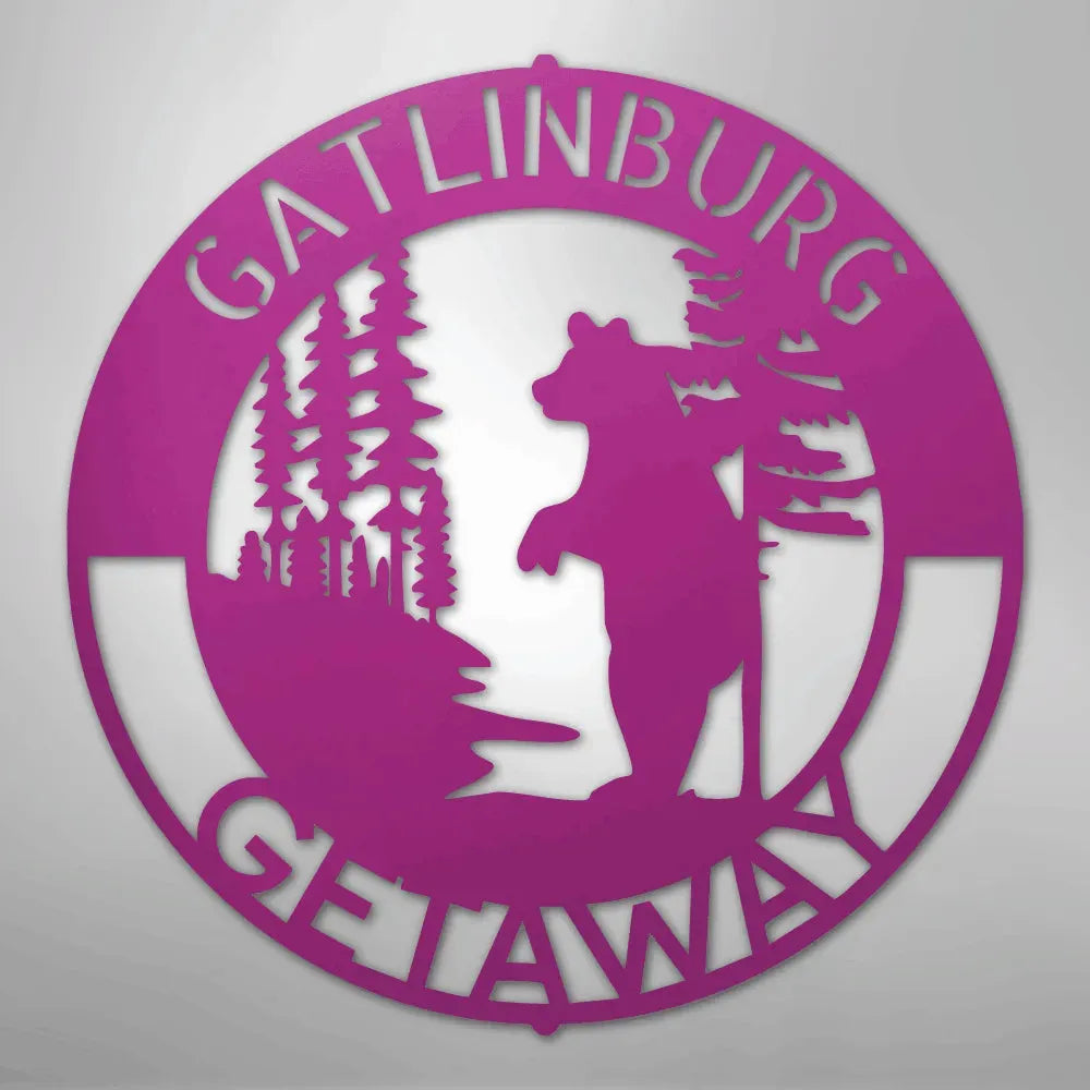 Pink metal wall art with "Gatlinburg Getaway" text, a standing bear, and pine trees.