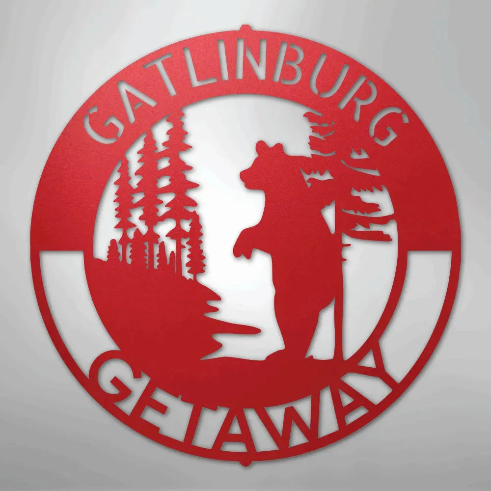 Red metal wall art with "Gatlinburg Getaway" text, a bear, and pine trees.