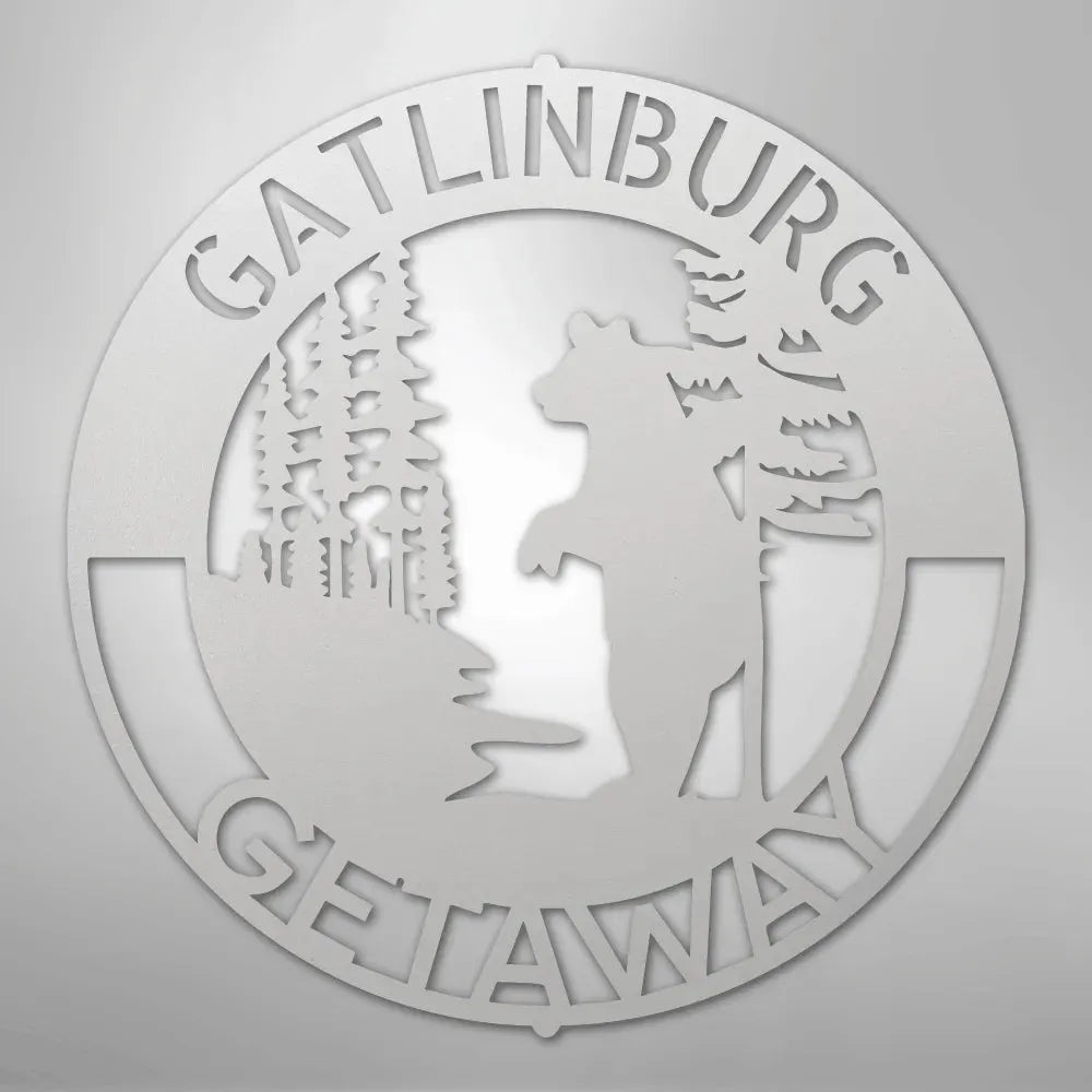 White metal wall art: "Gatlinburg Getaway" text, bear, and trees in a circular design.