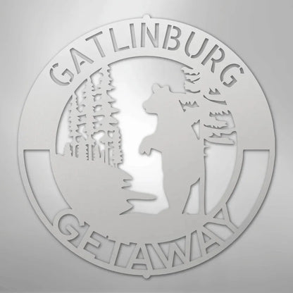 White metal wall art: "Gatlinburg Getaway" text, bear, and trees in a circular design.