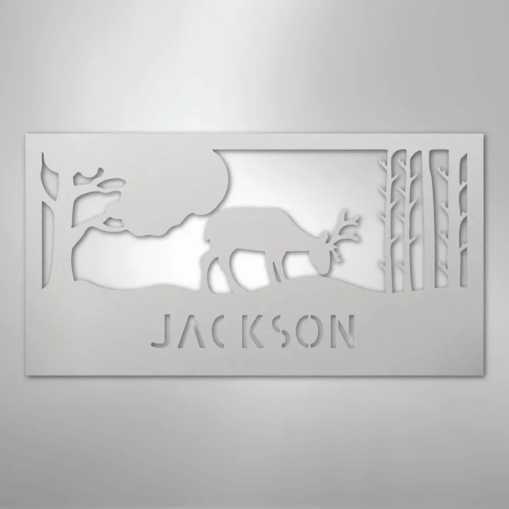 White metal wall art featuring a grazing deer, trees, and "JACKSON" cut out below.