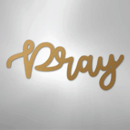Gold "Pray" script metal wall art with a textured finish, casting a shadow on a light background.