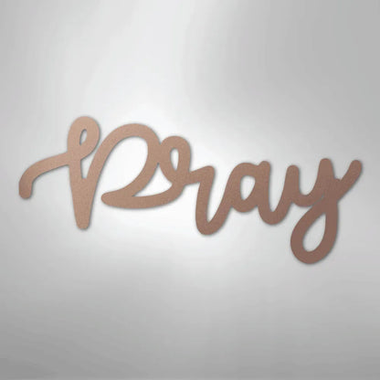 Rose gold "Pray" script metal wall art with a smooth finish, casting a subtle shadow.