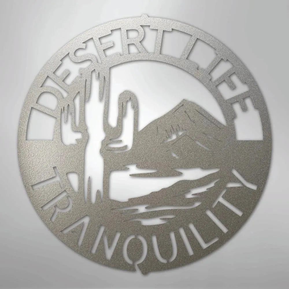 Circular silver metal wall art with "DESERT LIFE TRANQUILITY" text, saguaro cactus, and mountain design.