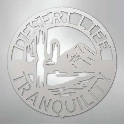 Round silver metal wall art with "DESERT LIFE TRANQUILITY" text, saguaro cactus, and mountains.