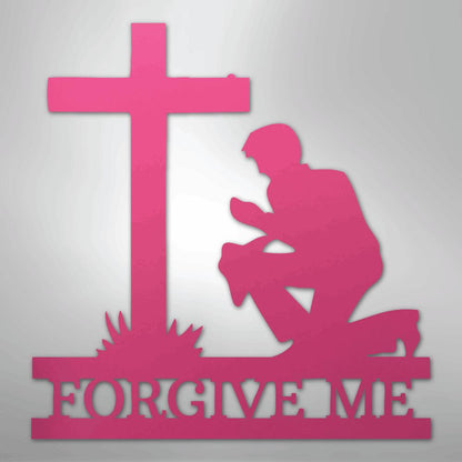 Pink metal wall art of a man kneeling before a cross with "FORGIVE ME" cut out below.