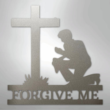 Silver metal wall art depicting a kneeling man praying before a cross, with "FORGIVE ME" cut out below.