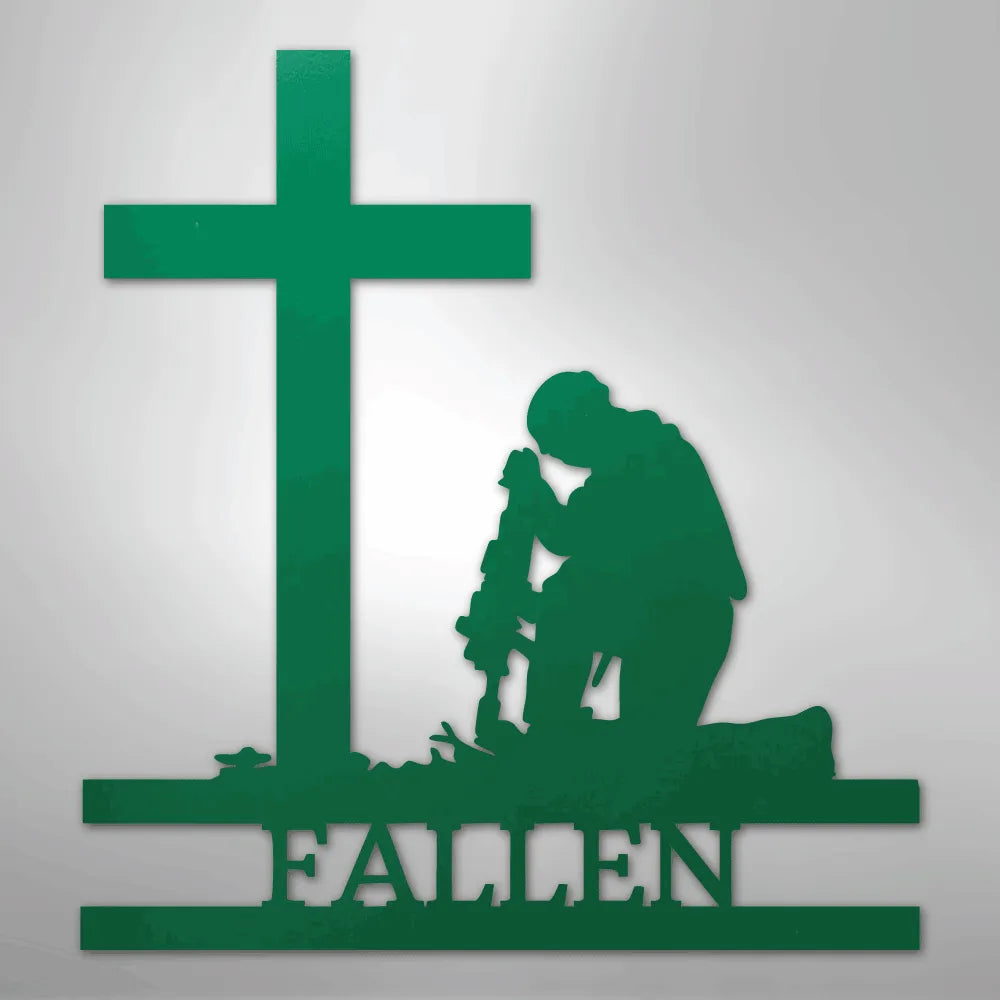 Green metal wall art of a kneeling soldier with a rifle before a cross and "FALLEN" text.