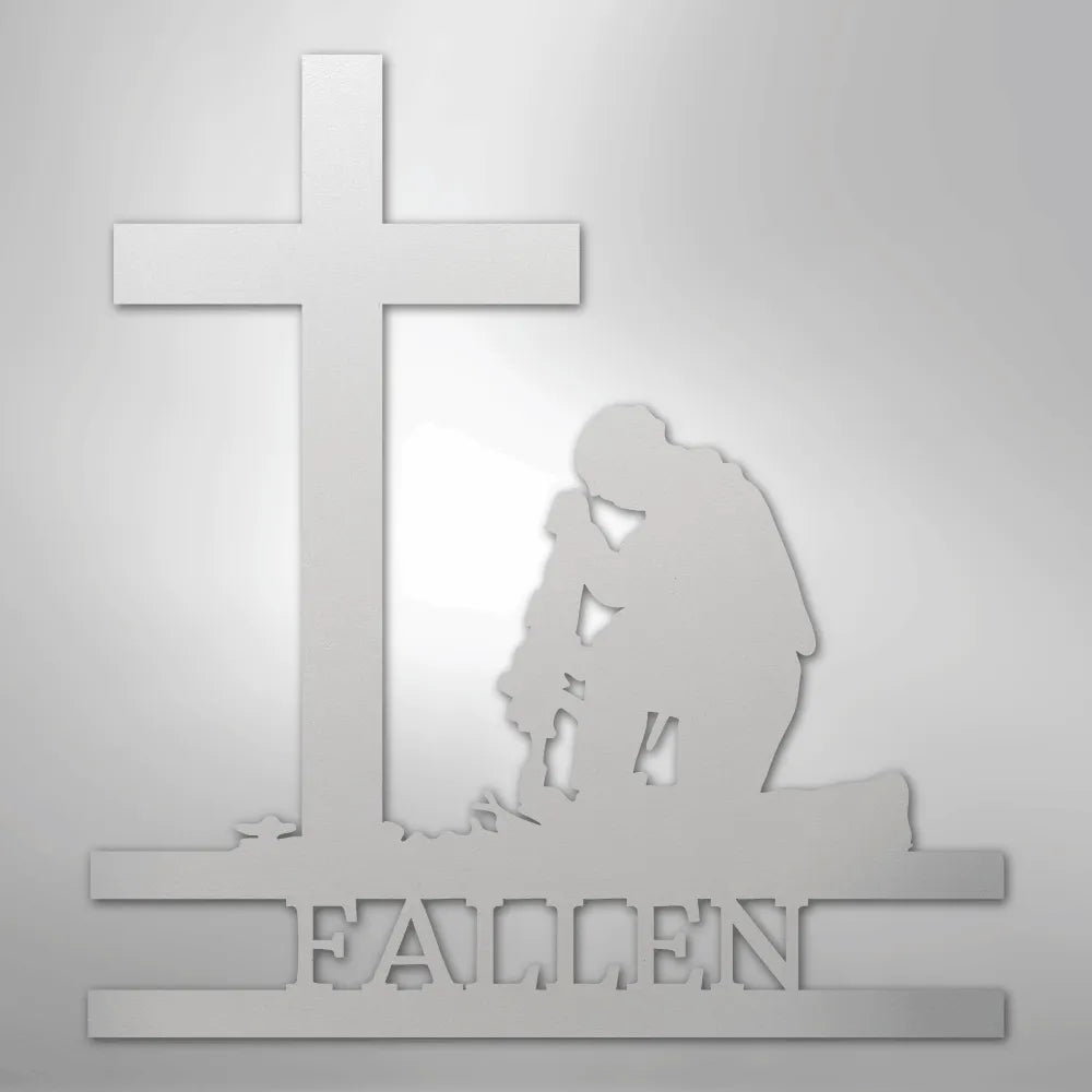 White metal wall art depicting a kneeling soldier silhouette before a cross, with "FALLEN" cut out below.