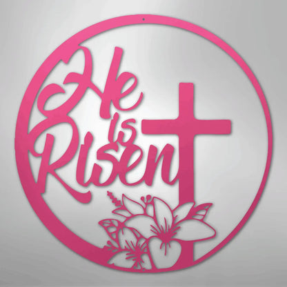 Pink "He is Risen" metal wall art with a cross and lilies inside a circular frame.