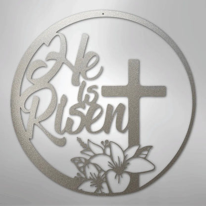Silver "He is Risen" metal wall art with a cross and lilies in a circular design.