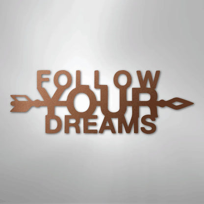 Copper "Follow Your Dreams" metal wall art with an arrow design, casting a shadow on a light background.