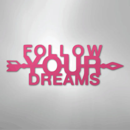 Pink metal wall art spelling "FOLLOW YOUR DREAMS" with an arrow design.