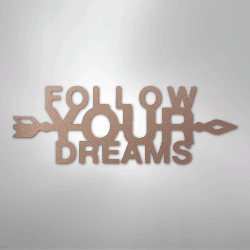 Copper metal wall art spelling "FOLLOW YOUR DREAMS" with an arrow design, casting a shadow.