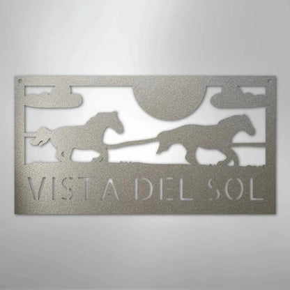 Silver metal sign with two racing horses, sun, clouds, and "VISTA DEL SOL" text.