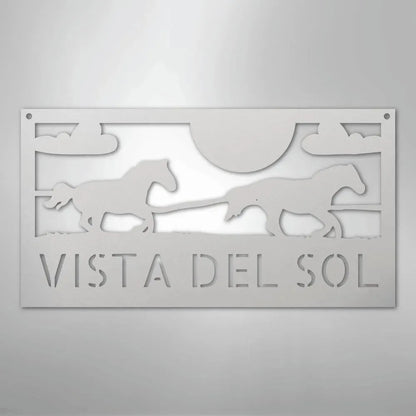 White metal address sign with two racing horses, sun, clouds, and "VISTA DEL SOL" text.