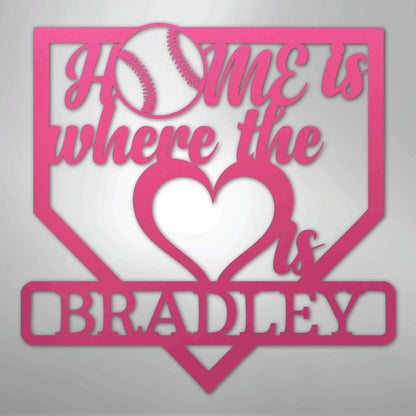 Pink metal baseball home plate sign with "Home is where the heart is Bradley" text and a baseball.