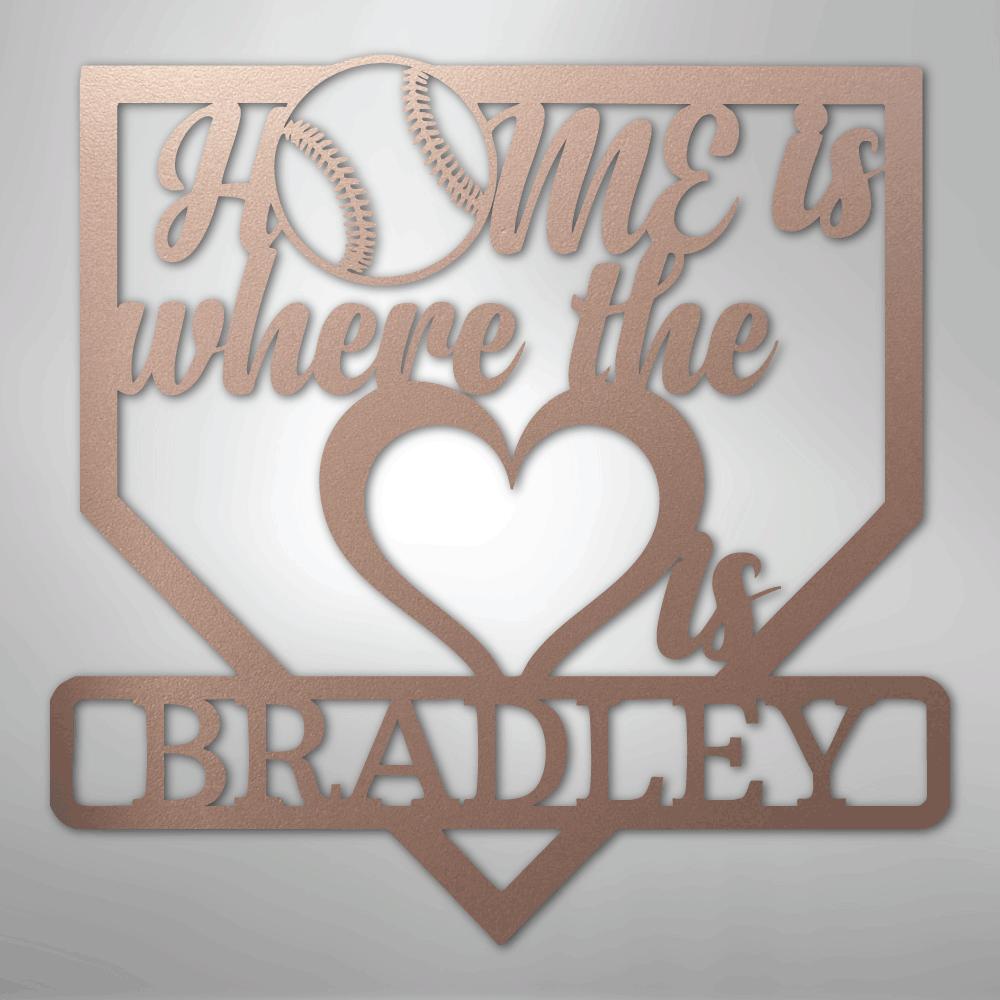 Rose gold metal baseball home plate sign with "Home is where the heart is Bradley" text.