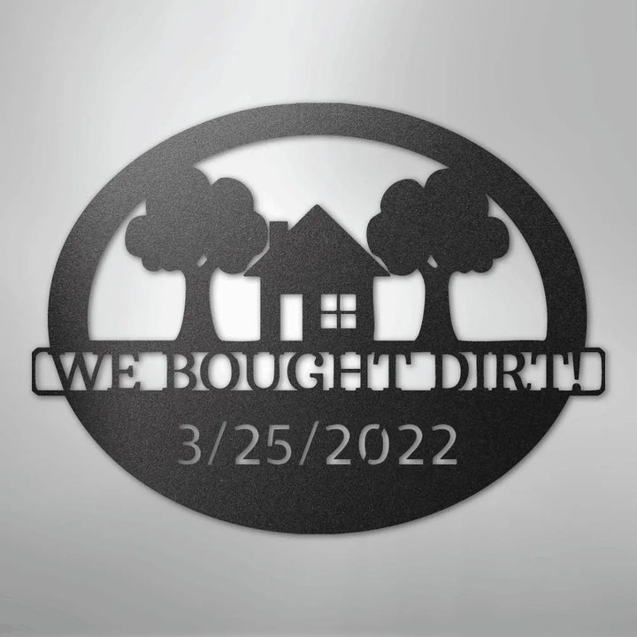 Black metal oval wall art with "WE BOUGHT DIRT!" and "3/25/2022" text, house, and trees.
