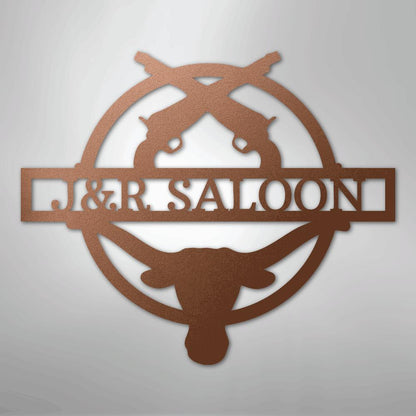 Copper metal "J&R SALOON" monogram with crossed pistols and longhorn skull, perfect for rustic decor.