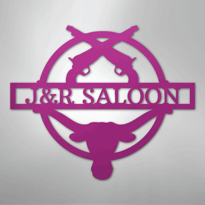 Pink metal "J&R Saloon" monogram with crossed pistols and a longhorn skull design.