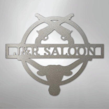 Silver metal "J&R Saloon" monogram wall art with crossed pistols and a longhorn skull design.