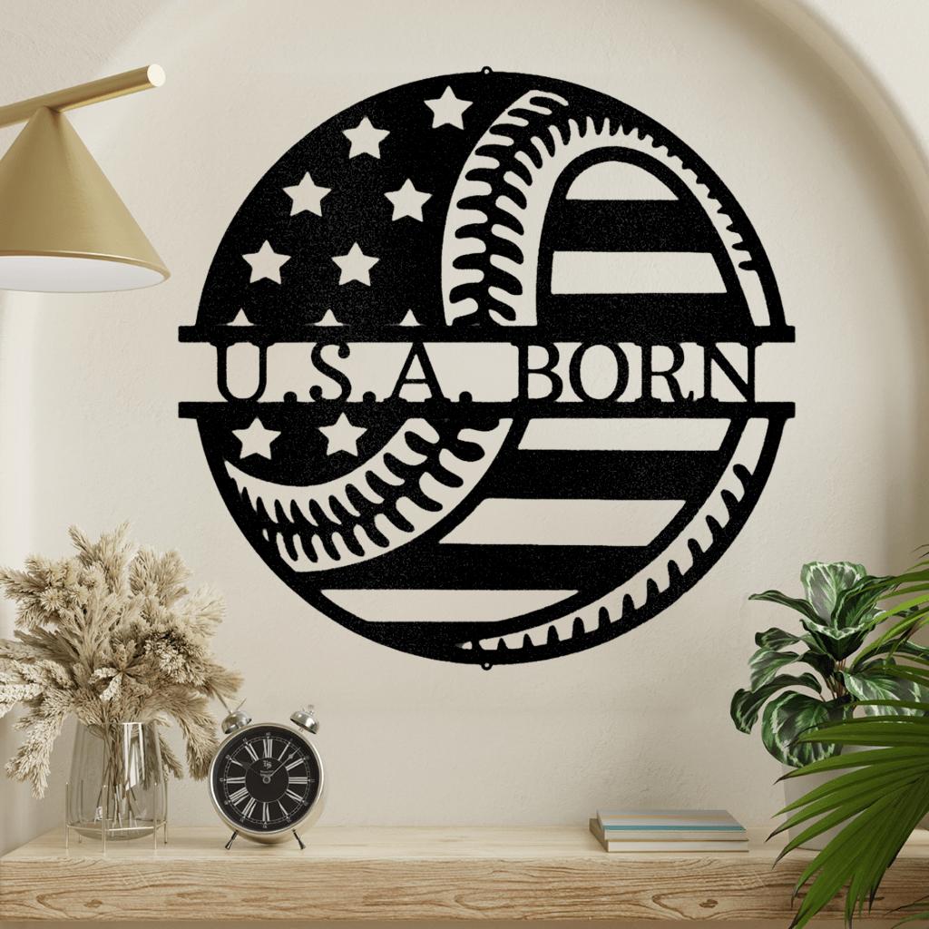 Black metal "U.S.A. BORN" sign with American flag and baseball stitching design.