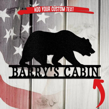 Black metal bear silhouette wall art with "Barry's Cabin" text, on a rustic American flag background.