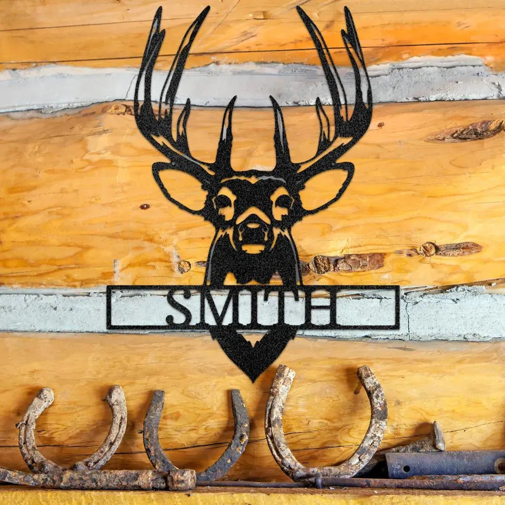 Black metal buck mount monogram with "SMITH" cut out, displayed on a rustic log wall.